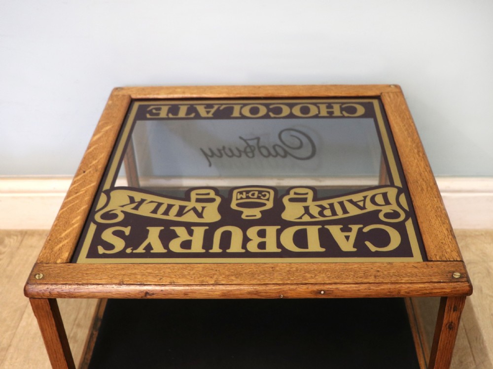 An early 20th-century oak countertop display cabinet featuring glazed panels and gold sign-written Cadburys Dairy Milk Chocolate lettering. View XXII