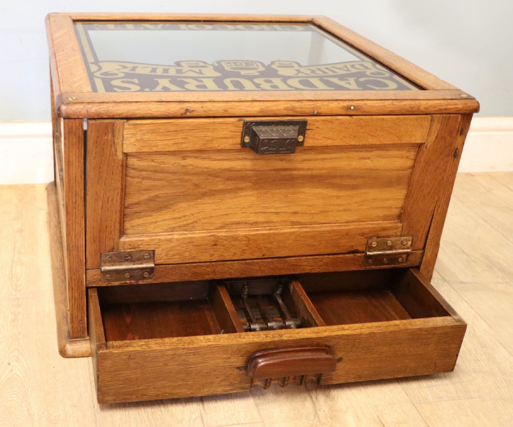 An early 20th-century oak countertop display cabinet featuring glazed panels and gold sign-written Cadburys Dairy Milk Chocolate lettering. View XXIII