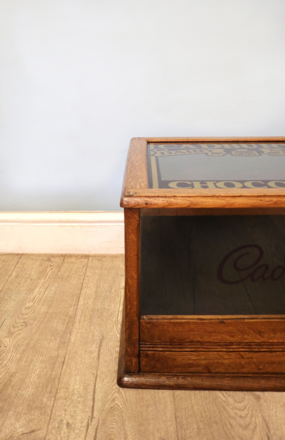 An early 20th-century oak countertop display cabinet featuring glazed panels and gold sign-written Cadburys Dairy Milk Chocolate lettering. View XXIV