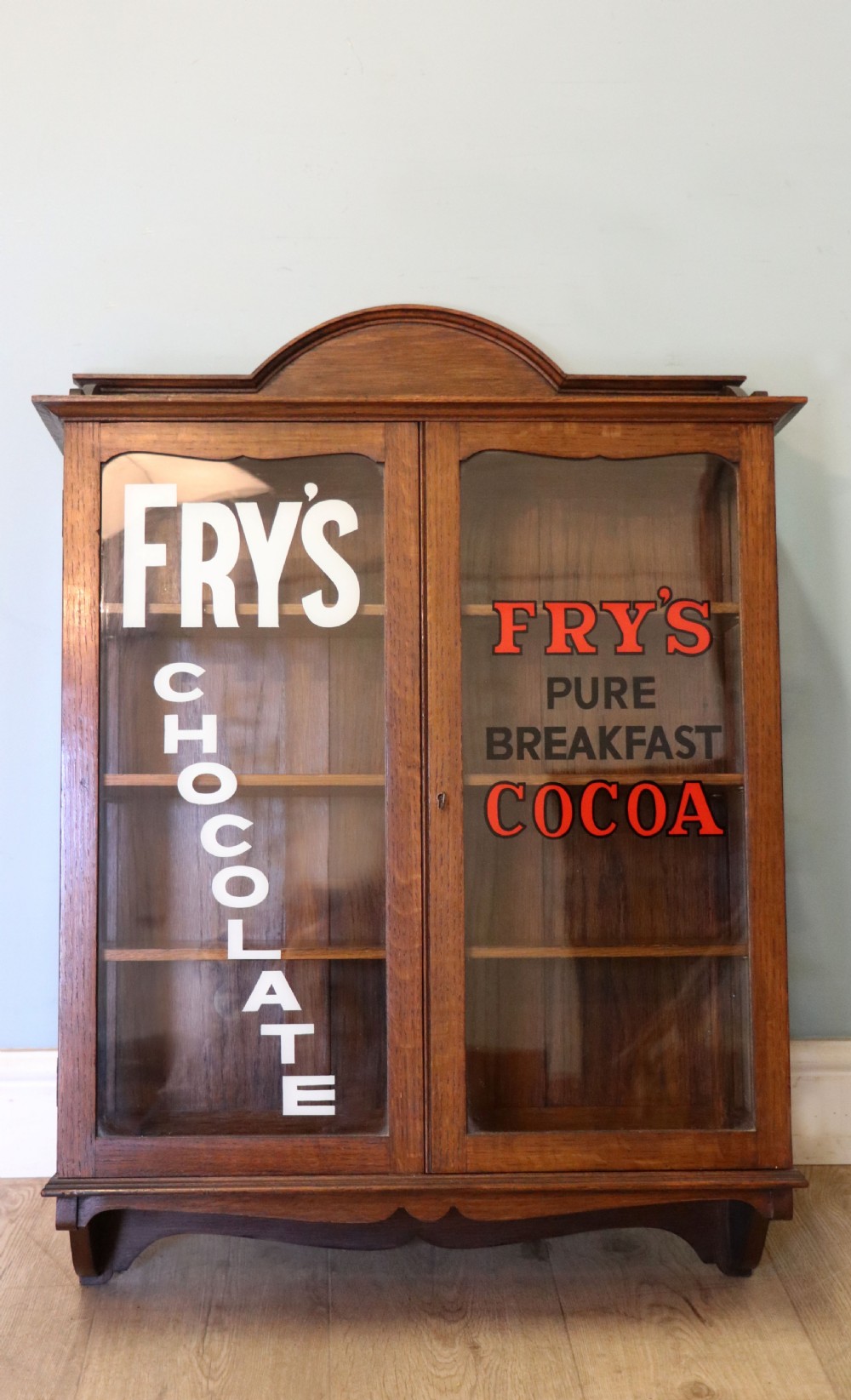  A wonderful Edwardian wall mounted solid oak framed display cabinet,  later sign written advertising Fry's Chocolate. View II