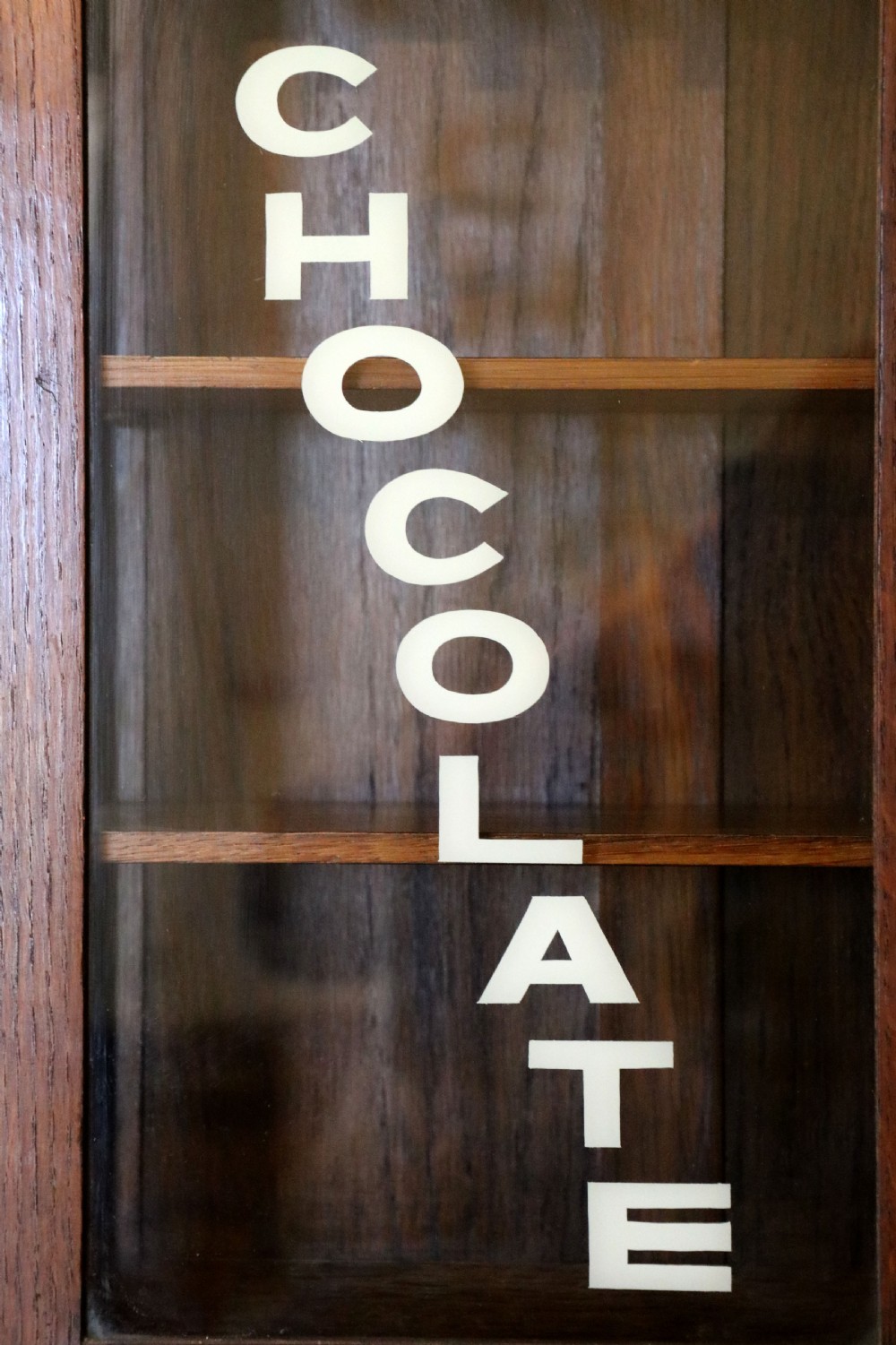  A wonderful Edwardian wall mounted solid oak framed display cabinet,  later sign written advertising Fry's Chocolate. View IX