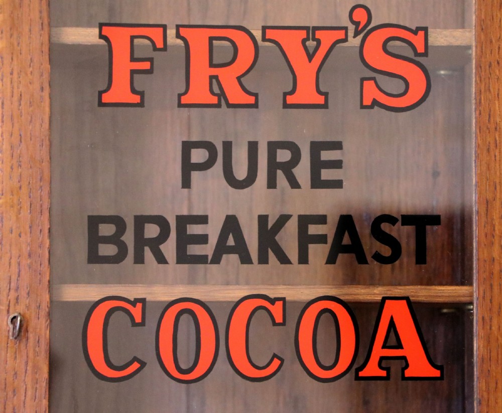  A wonderful Edwardian wall mounted solid oak framed display cabinet,  later sign written advertising Fry's Chocolate. View X