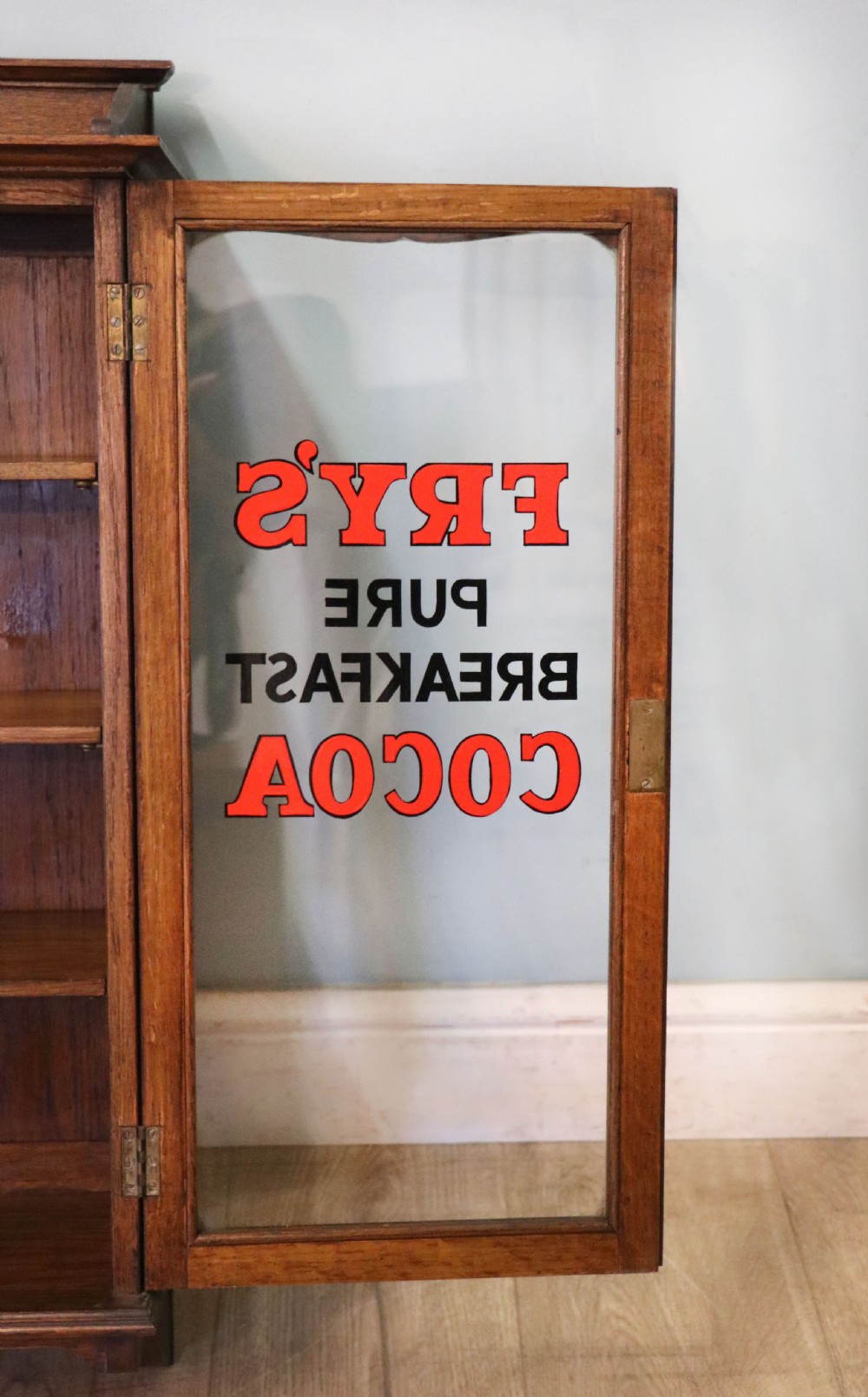  A wonderful Edwardian wall mounted solid oak framed display cabinet,  later sign written advertising Fry's Chocolate. View XIV