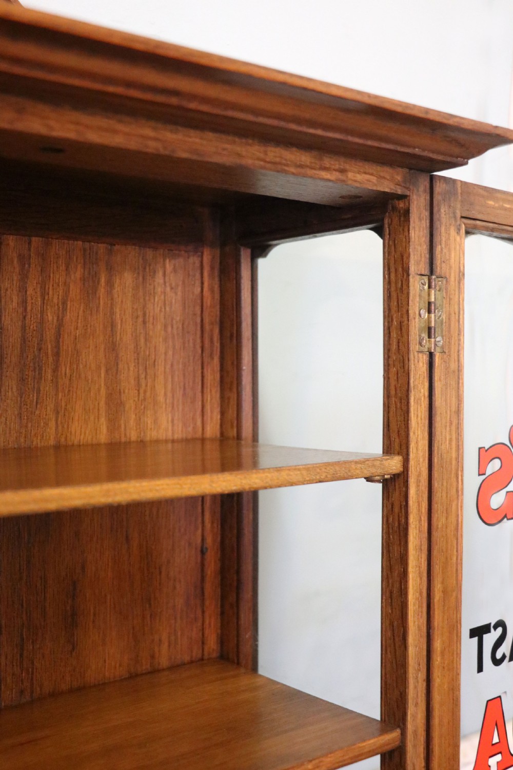  A wonderful Edwardian wall mounted solid oak framed display cabinet,  later sign written advertising Fry's Chocolate. View XVII