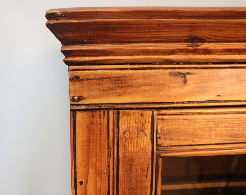 A glazed pine cabinet featuring a glass door with gold and red bakery signwriting and internal wooden shelves. View IX