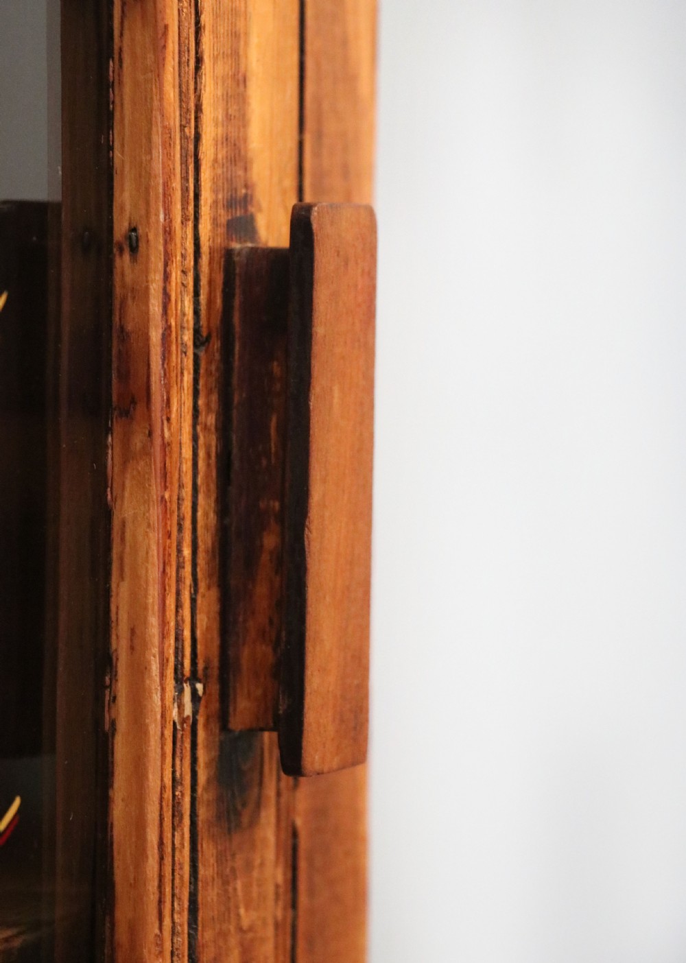 A glazed pine cabinet featuring a glass door with gold and red bakery signwriting and internal wooden shelves. View XVI