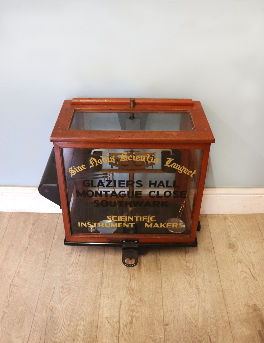 A set of brass chemist precision beam scales enclosed within a glazed mahogany display case featuring gilt and black sign-written lettering. View III