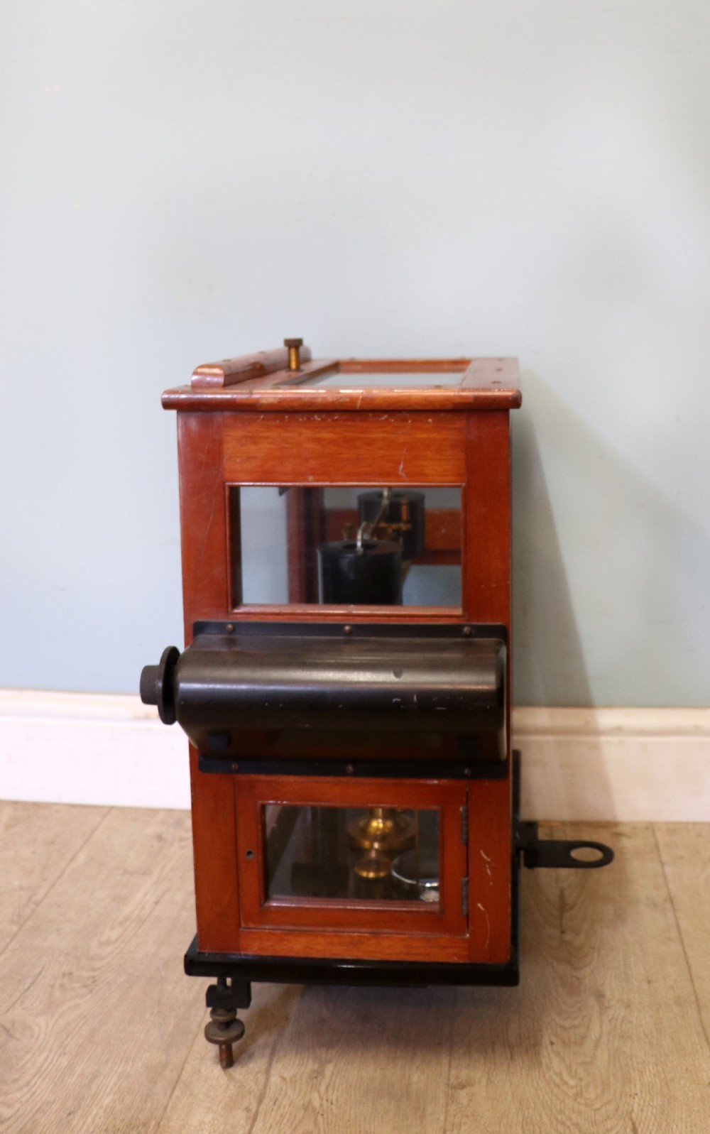 A set of brass chemist precision beam scales enclosed within a glazed mahogany display case featuring gilt and black sign-written lettering. View IV