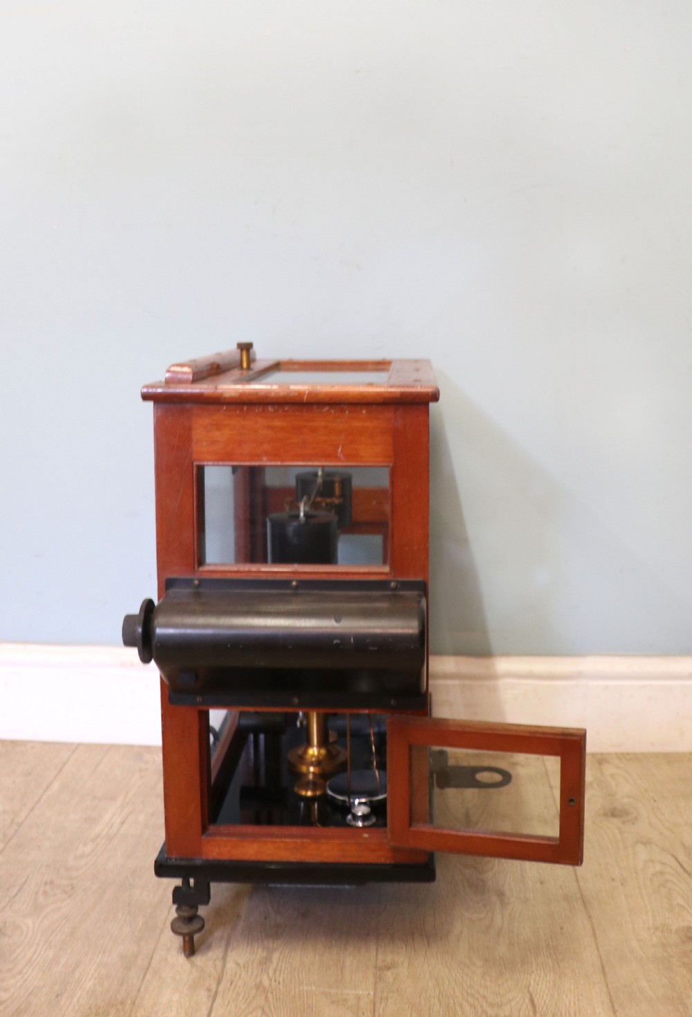 A set of brass chemist precision beam scales enclosed within a glazed mahogany display case featuring gilt and black sign-written lettering. View V