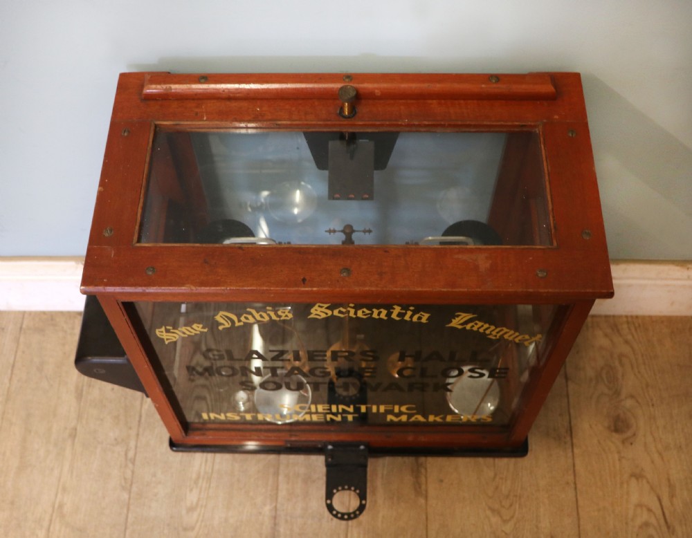 A set of brass chemist precision beam scales enclosed within a glazed mahogany display case featuring gilt and black sign-written lettering. View VI