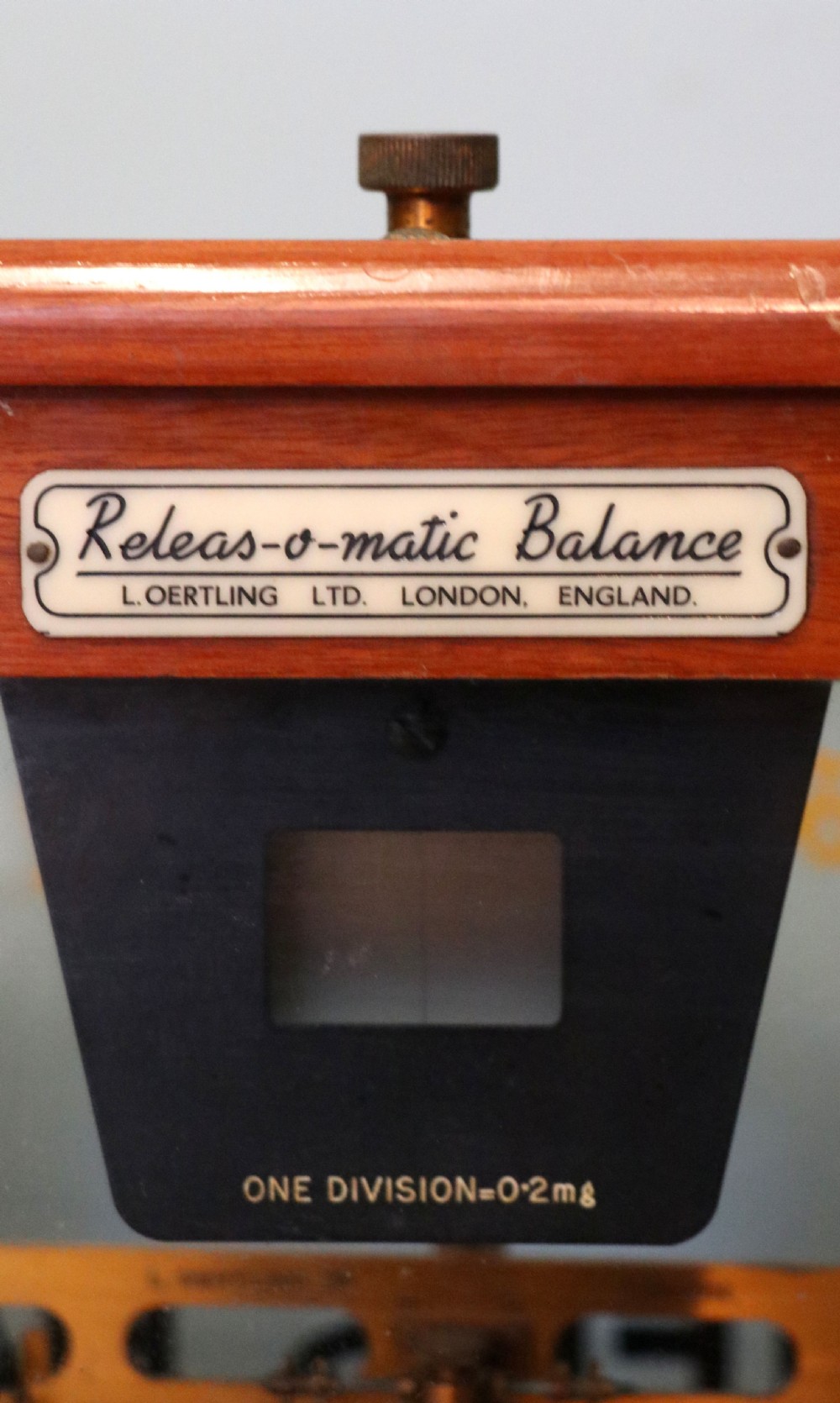 A set of brass chemist precision beam scales enclosed within a glazed mahogany display case featuring gilt and black sign-written lettering. View IX