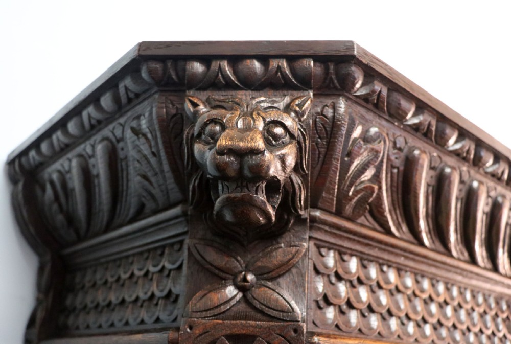 A late 19th-century dark oak glazed display cabinet on a tall stand featuring detailed lion mask relief carvings and hand-painted German heraldic emblems on the glass doors. View IX