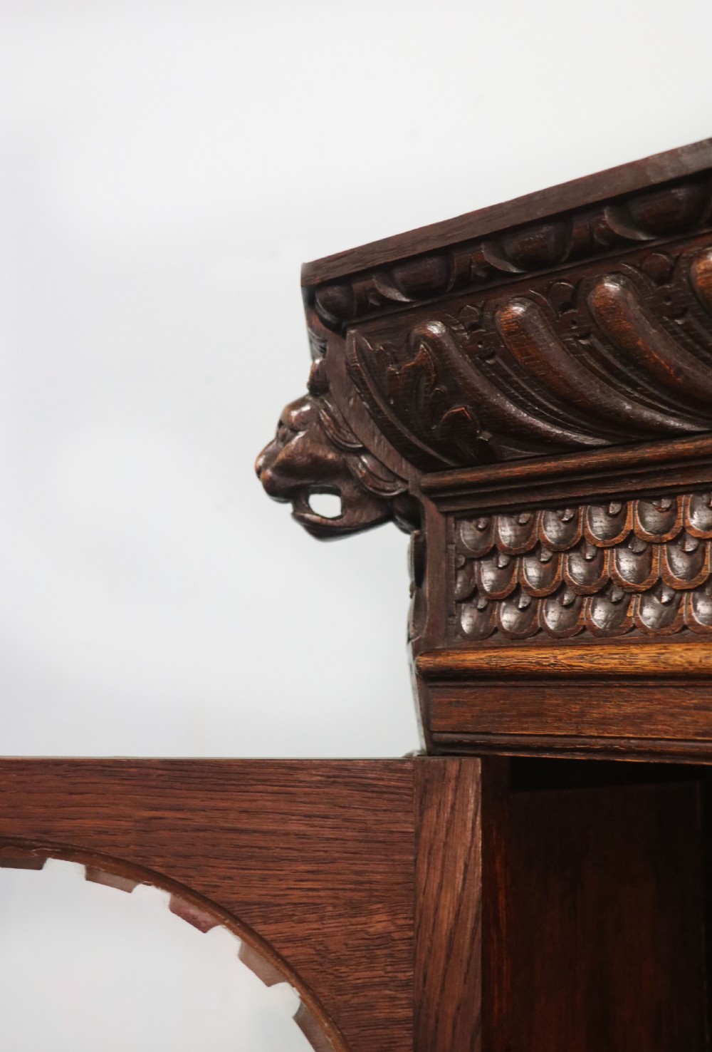 A late 19th-century dark oak glazed display cabinet on a tall stand featuring detailed lion mask relief carvings and hand-painted German heraldic emblems on the glass doors. View XI
