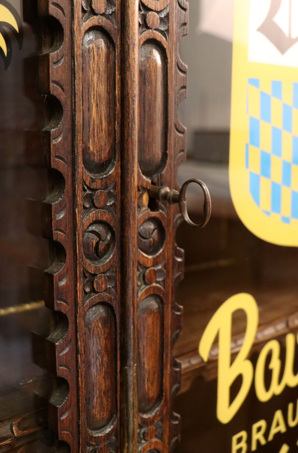 A late 19th-century dark oak glazed display cabinet on a tall stand featuring detailed lion mask relief carvings and hand-painted German heraldic emblems on the glass doors. View XXIV