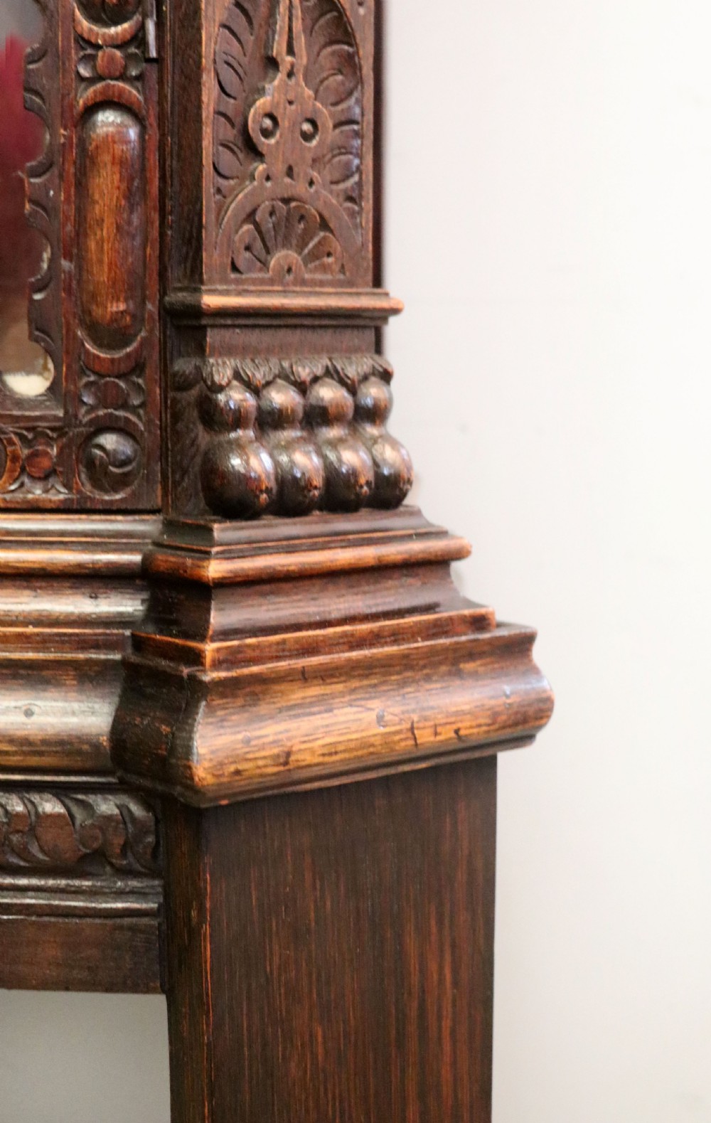 A late 19th-century dark oak glazed display cabinet on a tall stand featuring detailed lion mask relief carvings and hand-painted German heraldic emblems on the glass doors. View XXV