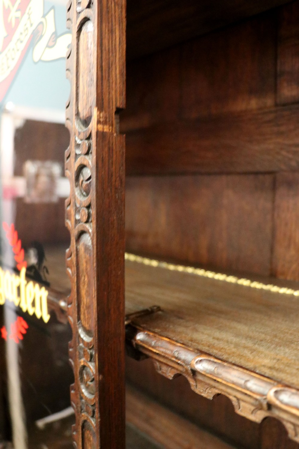 A late 19th-century dark oak glazed display cabinet on a tall stand featuring detailed lion mask relief carvings and hand-painted German heraldic emblems on the glass doors. View XXXI