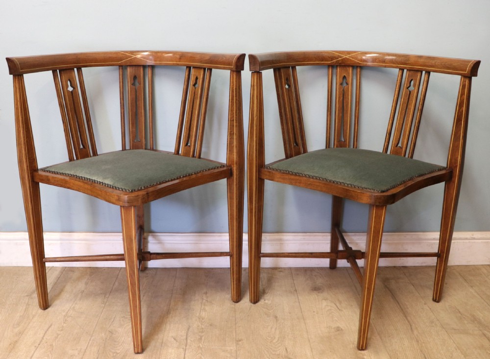 A pair of antique mahogany corner chairs featuring boxwood line inlay, pierced back splats, cross-braced legs, and green upholstered seats with stud trim.