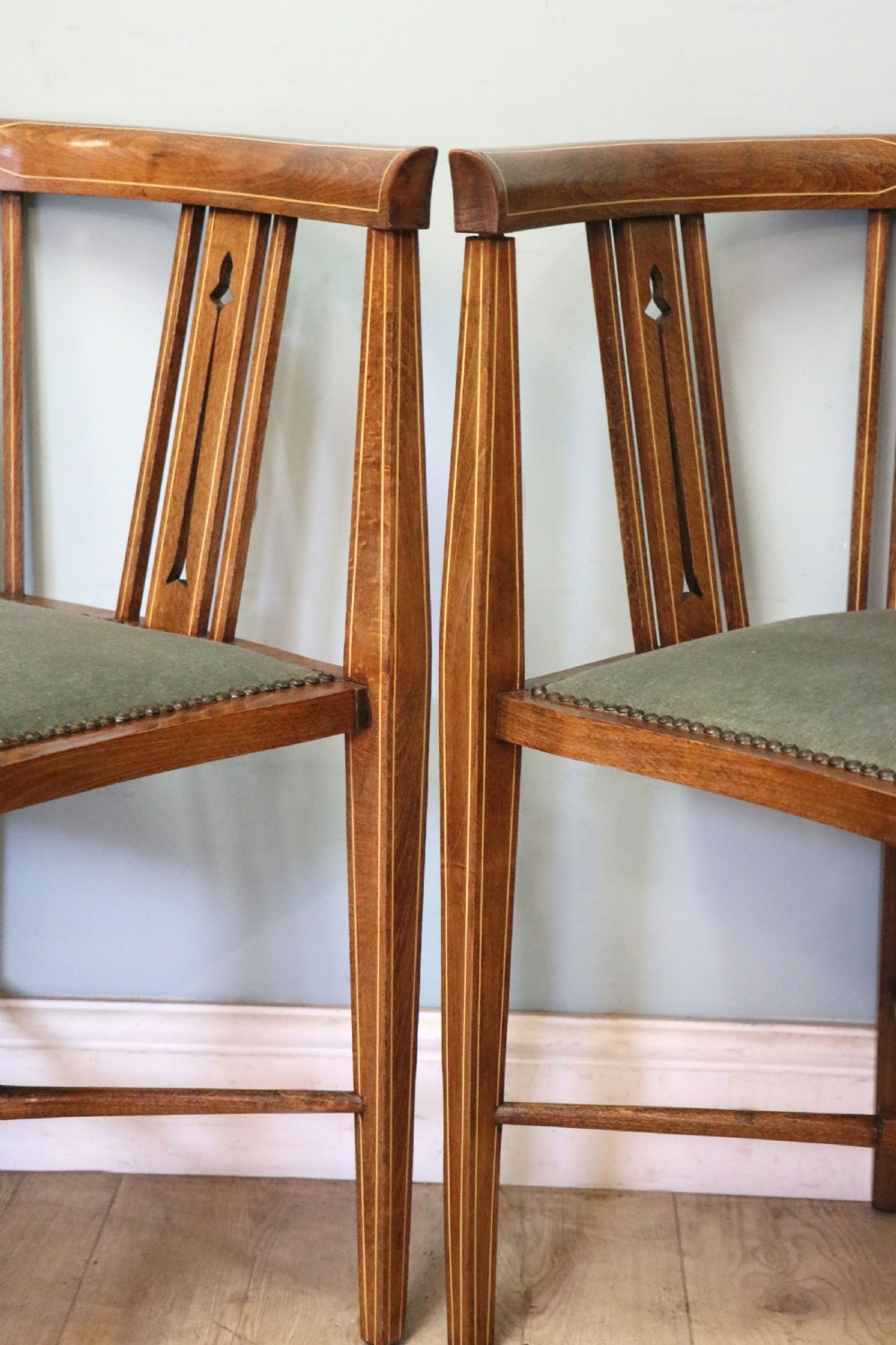 A pair of antique mahogany corner chairs featuring boxwood line inlay, pierced back splats, cross-braced legs, and green upholstered seats with stud trim. View XIX