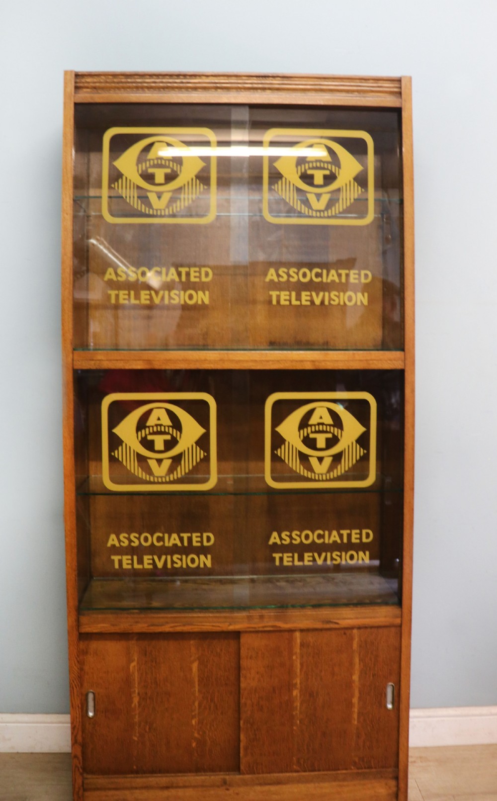  A 1930s/ 1940s oak bookcase or display cabinet decorated with the Associated Television logo.