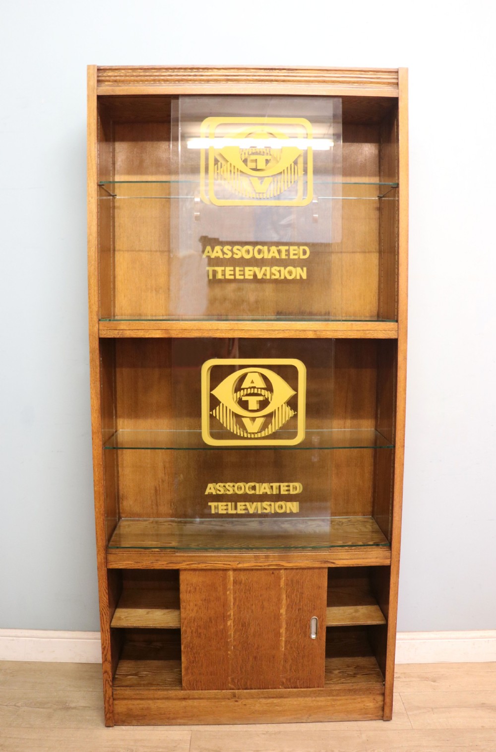  A 1930s/ 1940s oak bookcase or display cabinet decorated with the Associated Television logo. View II