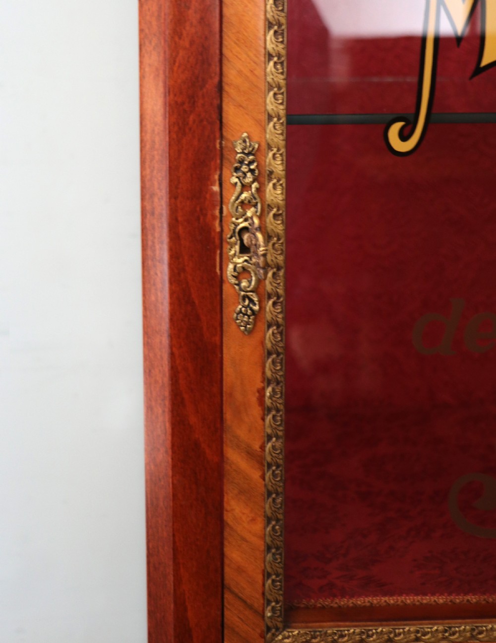 A French Vernis Martin style mahogany vitrine cabinet featuring a brass top gallery, glass shelves, red fabric lining, and a glazed door with gilded lettering. View XIV
