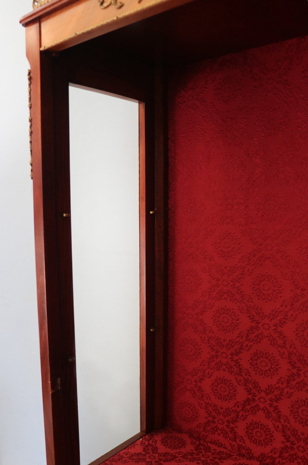 A French Vernis Martin style mahogany vitrine cabinet featuring a brass top gallery, glass shelves, red fabric lining, and a glazed door with gilded lettering. View XX