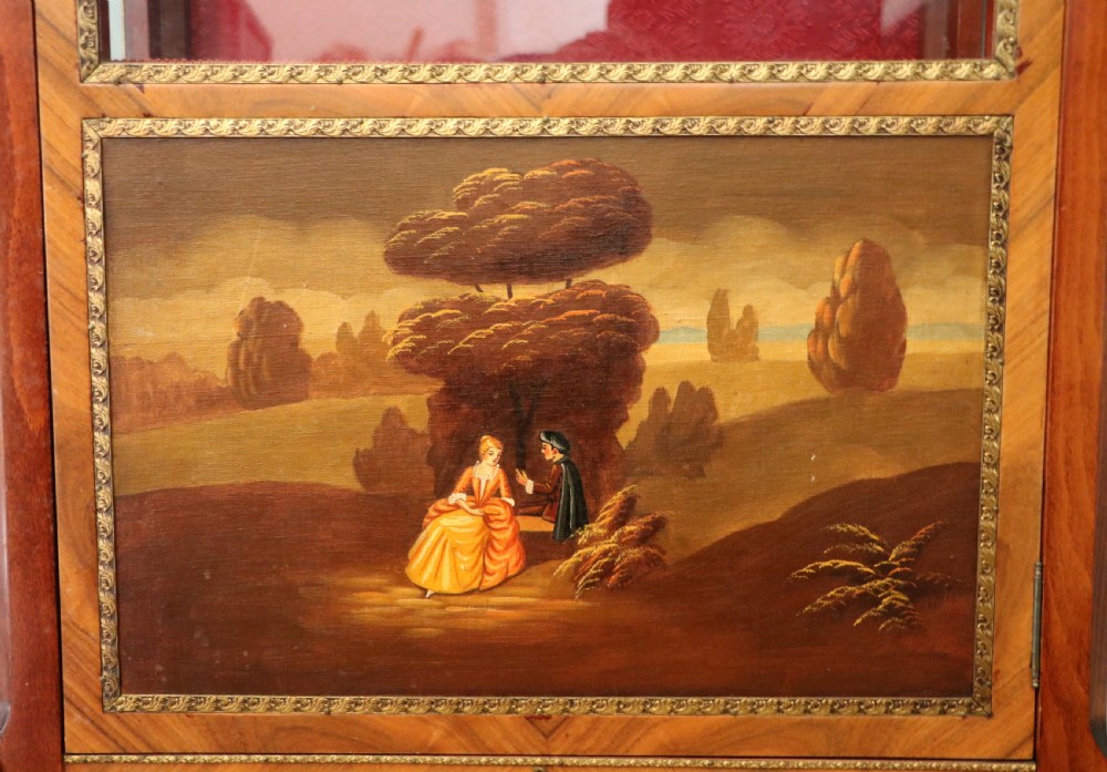 A French Vernis Martin style mahogany vitrine cabinet featuring a brass top gallery, glass shelves, red fabric lining, and a glazed door with gilded lettering. View XXVII