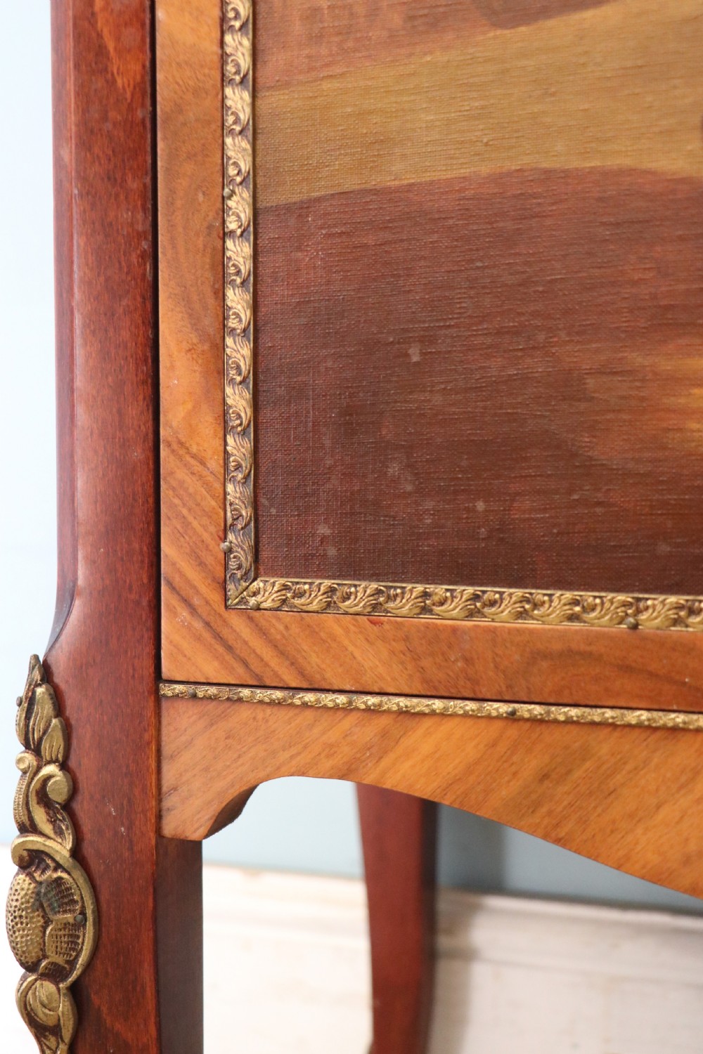 A French Vernis Martin style mahogany vitrine cabinet featuring a brass top gallery, glass shelves, red fabric lining, and a glazed door with gilded lettering. View XXX