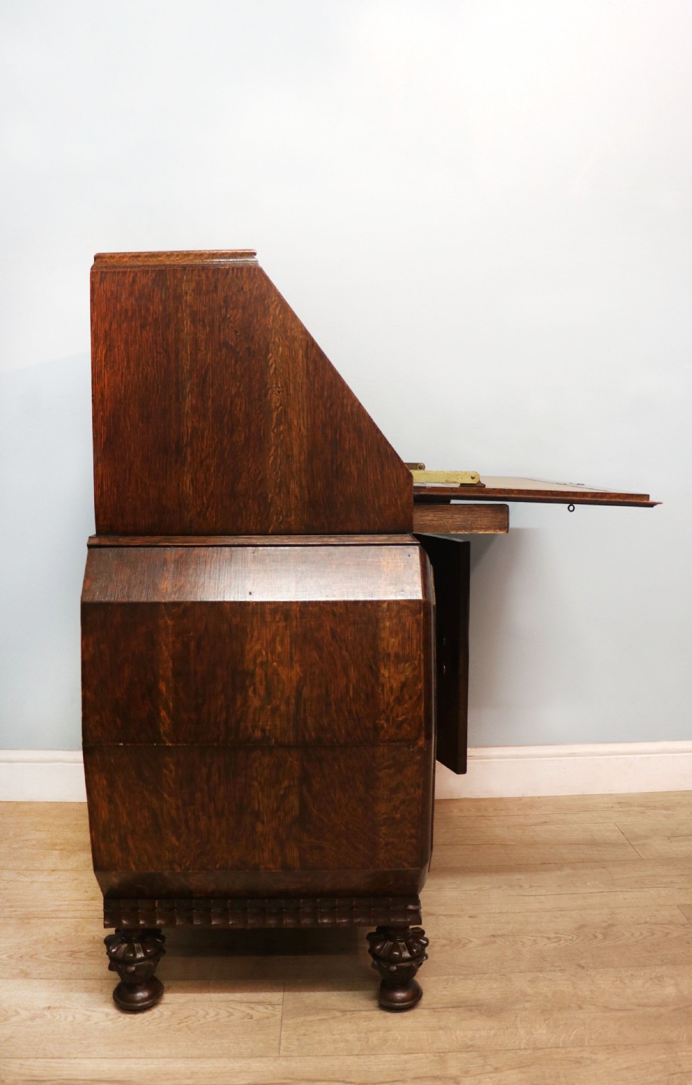 A dark oak fall-front bureau with octagonal geometric cupboard doors, carved details, turned gadrooned feet, and an open fitted stationery compartment. View IX