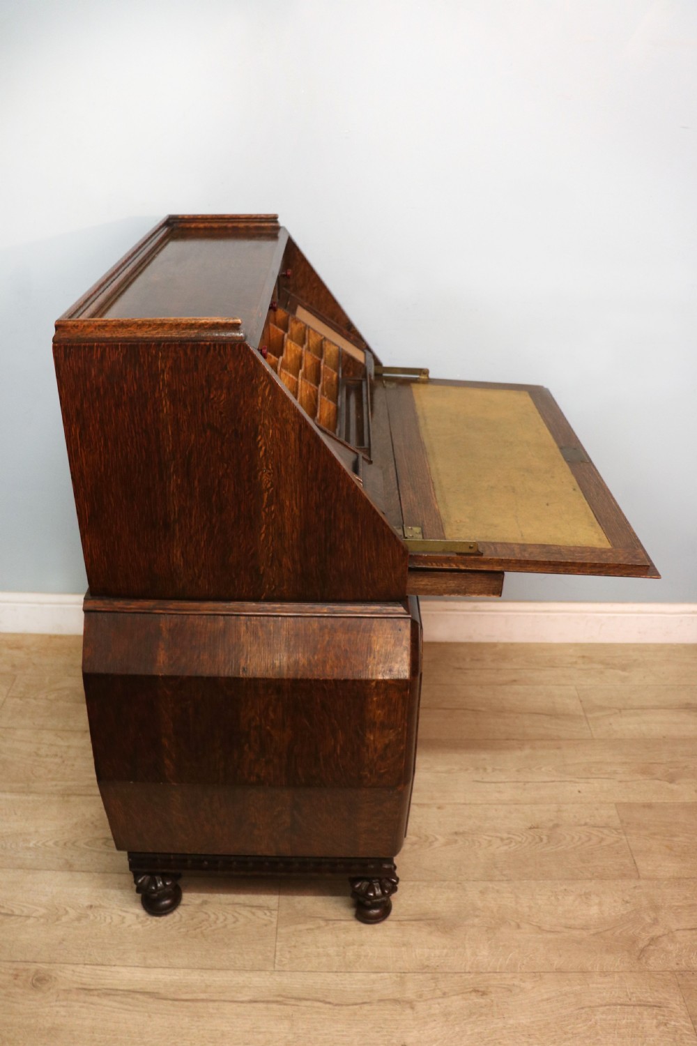 A dark oak fall-front bureau with octagonal geometric cupboard doors, carved details, turned gadrooned feet, and an open fitted stationery compartment. View X