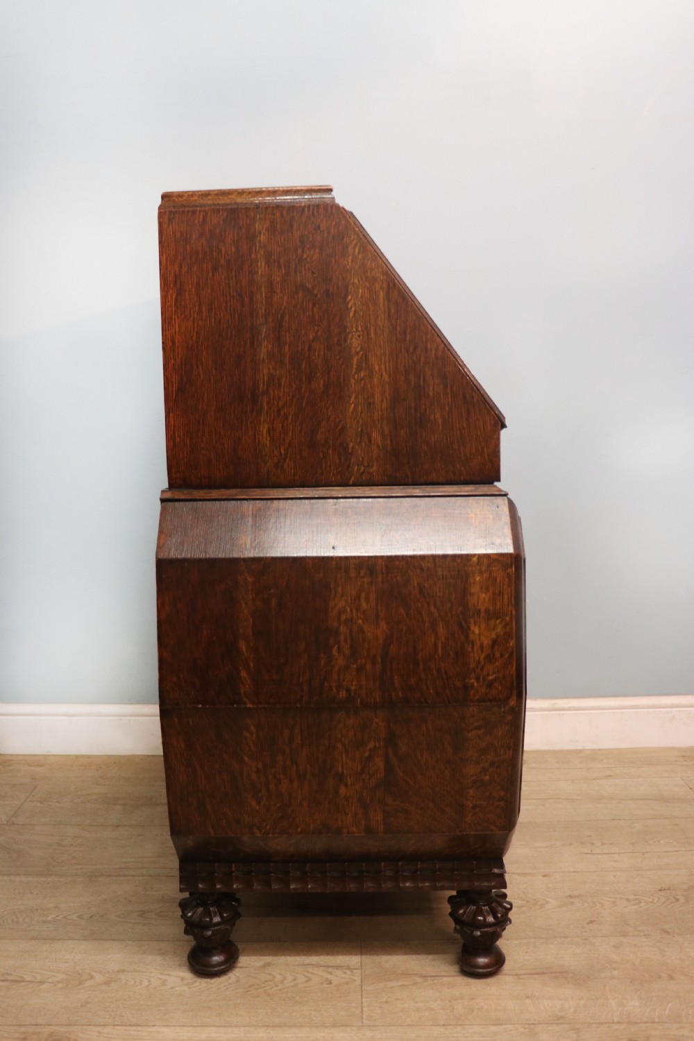 A dark oak fall-front bureau with octagonal geometric cupboard doors, carved details, turned gadrooned feet, and an open fitted stationery compartment. View XI