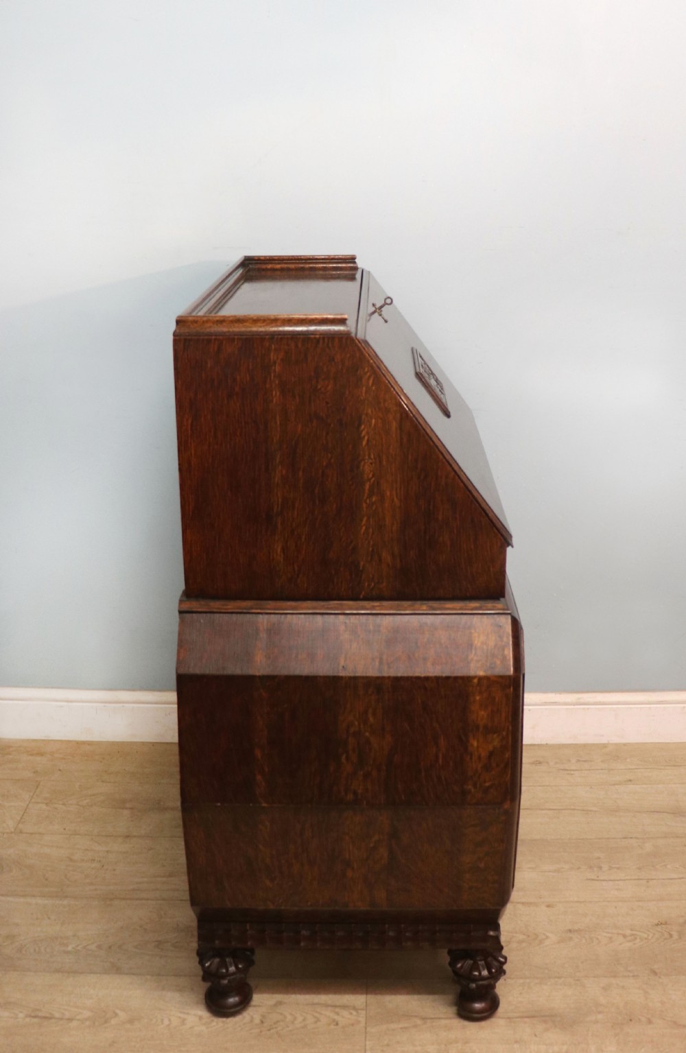A dark oak fall-front bureau with octagonal geometric cupboard doors, carved details, turned gadrooned feet, and an open fitted stationery compartment. View XII