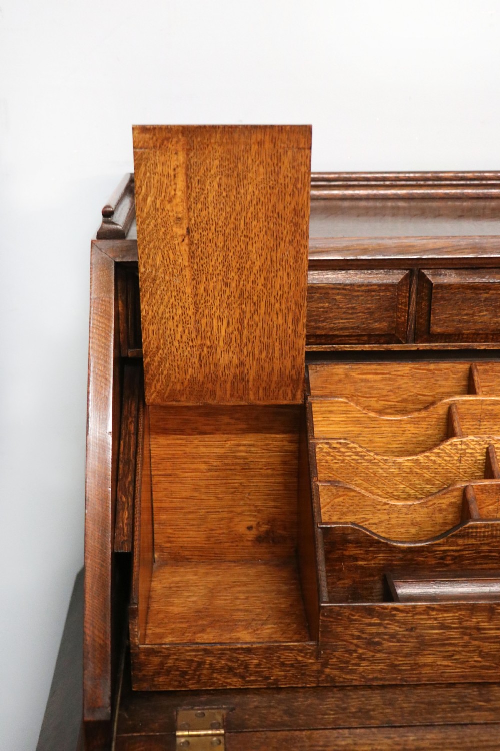 A dark oak fall-front bureau with octagonal geometric cupboard doors, carved details, turned gadrooned feet, and an open fitted stationery compartment. View XXV