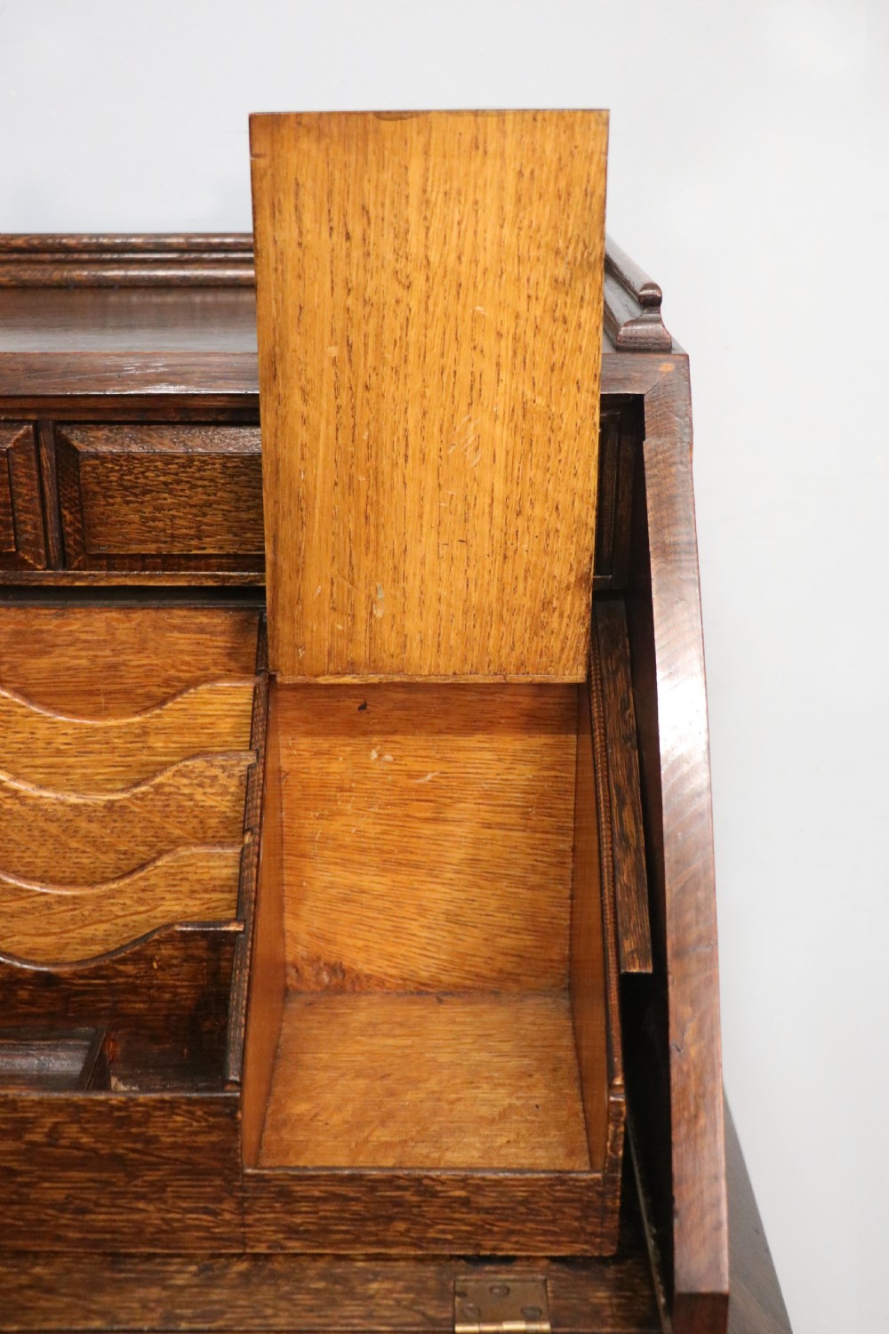 A dark oak fall-front bureau with octagonal geometric cupboard doors, carved details, turned gadrooned feet, and an open fitted stationery compartment. View XXVIII