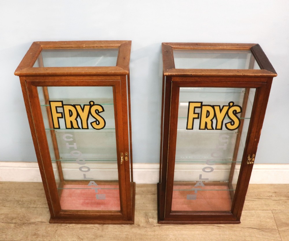 A pair of early 20th-century wooden glazed counter display cabinets featuring sign-written Frys Chocolate lettering on the front glass panels and interior glass shelves. View II