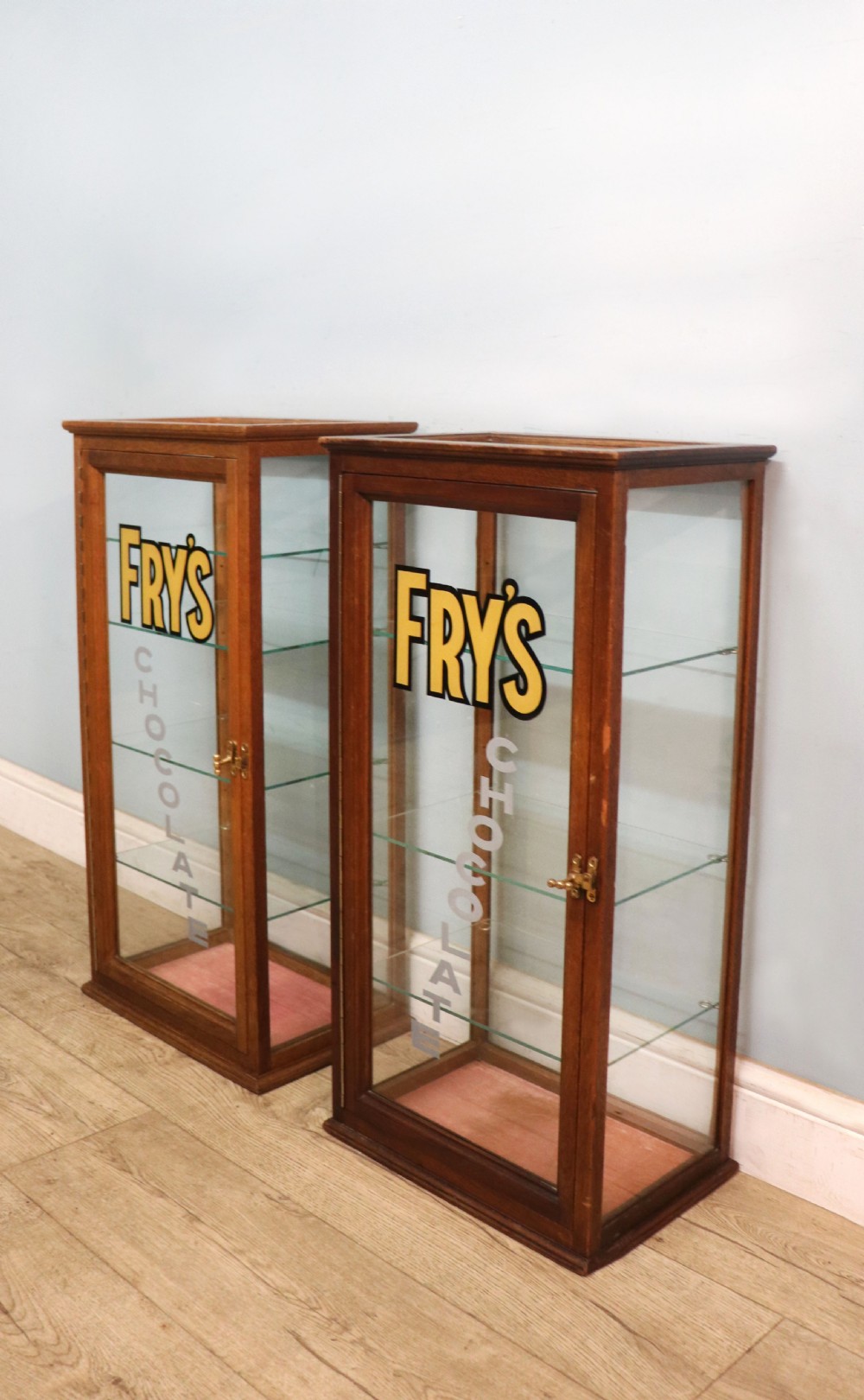 A pair of early 20th-century wooden glazed counter display cabinets featuring sign-written Frys Chocolate lettering on the front glass panels and interior glass shelves. View III