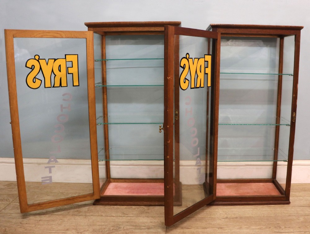 A pair of early 20th-century wooden glazed counter display cabinets featuring sign-written Frys Chocolate lettering on the front glass panels and interior glass shelves. View IV