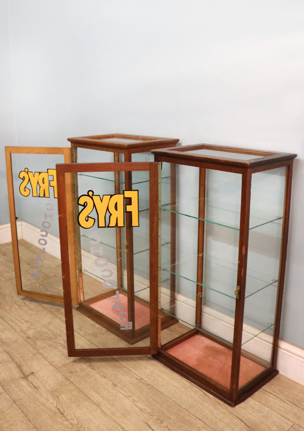A pair of early 20th-century wooden glazed counter display cabinets featuring sign-written Frys Chocolate lettering on the front glass panels and interior glass shelves. View VI