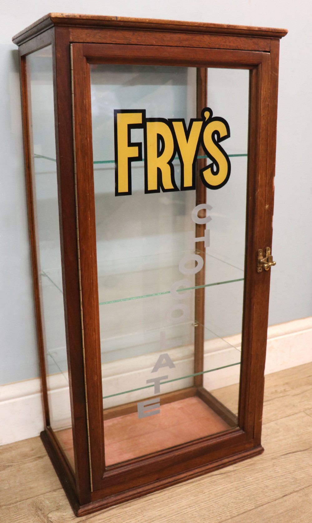 A pair of early 20th-century wooden glazed counter display cabinets featuring sign-written Frys Chocolate lettering on the front glass panels and interior glass shelves. View VII