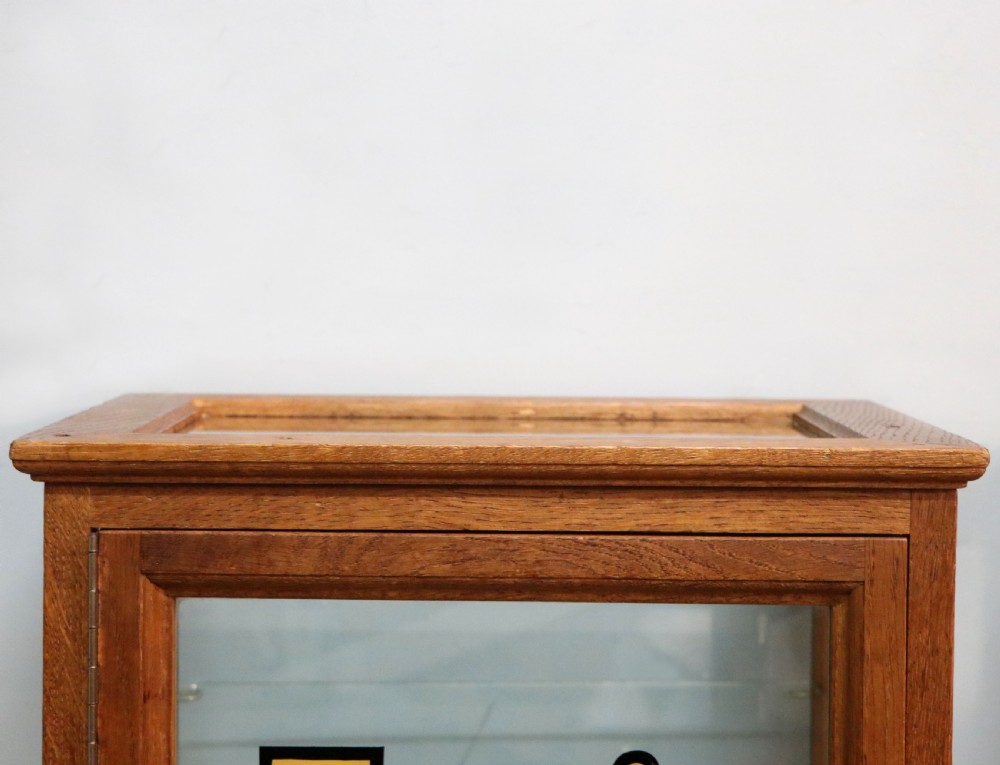 A pair of early 20th-century wooden glazed counter display cabinets featuring sign-written Frys Chocolate lettering on the front glass panels and interior glass shelves. View IX