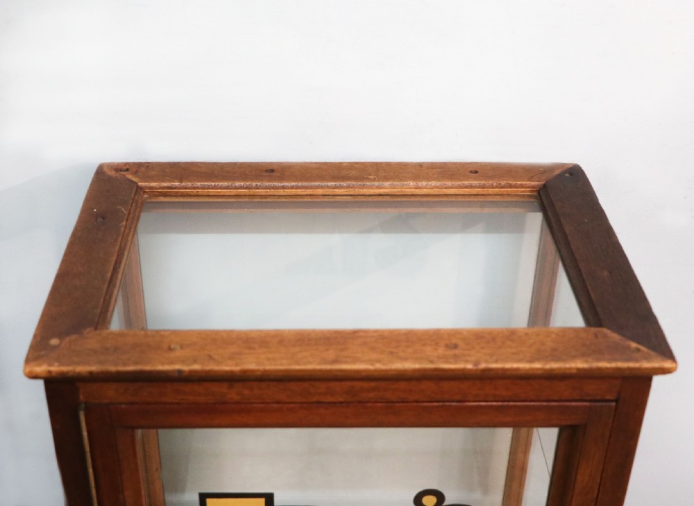 A pair of early 20th-century wooden glazed counter display cabinets featuring sign-written Frys Chocolate lettering on the front glass panels and interior glass shelves. View X