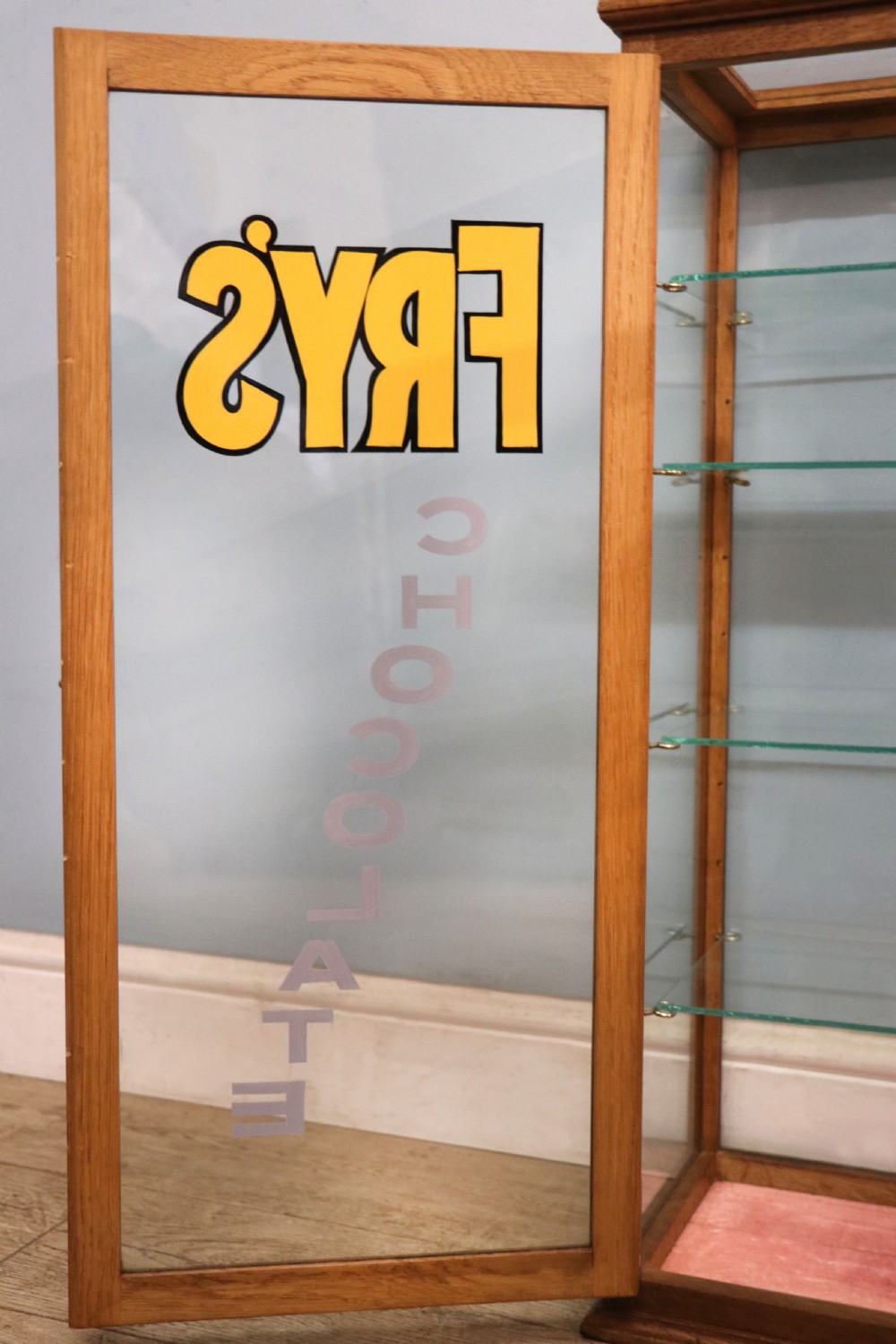 A pair of early 20th-century wooden glazed counter display cabinets featuring sign-written Frys Chocolate lettering on the front glass panels and interior glass shelves. View XV
