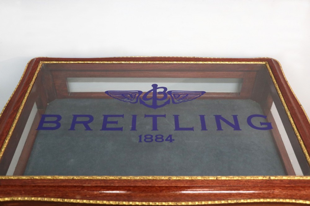A French Louis XV style glazed bijouterie table in dark hardwood with cabriole legs, gilt metal mounts, and blue Breitling lettering on the glass top. View VIII