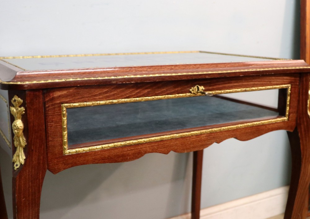 A French Louis XV style glazed bijouterie table in dark hardwood with cabriole legs, gilt metal mounts, and blue Breitling lettering on the glass top. View XI