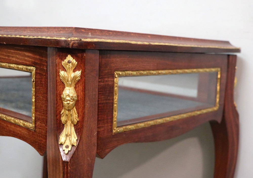 A French Louis XV style glazed bijouterie table in dark hardwood with cabriole legs, gilt metal mounts, and blue Breitling lettering on the glass top. View XIII