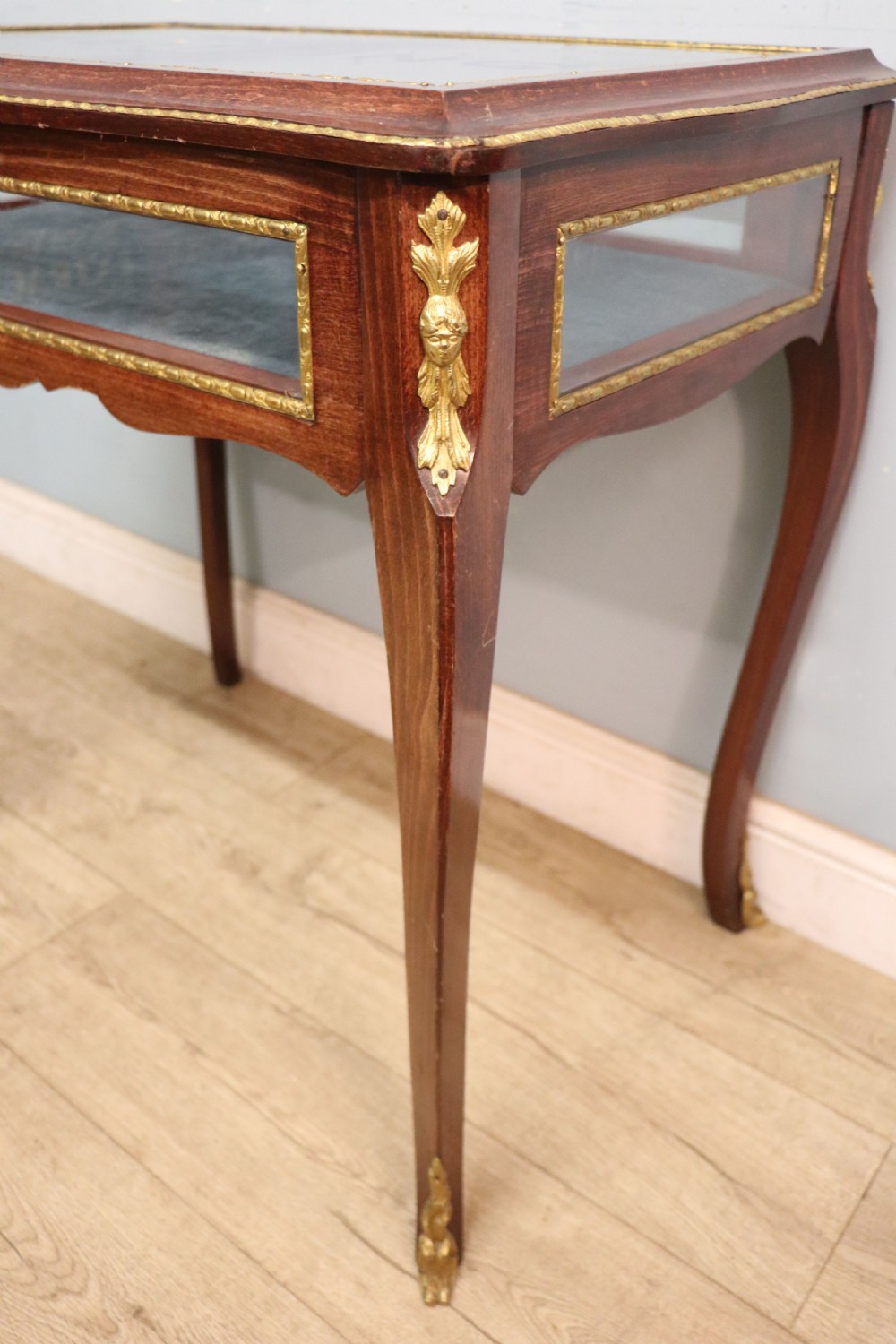 A French Louis XV style glazed bijouterie table in dark hardwood with cabriole legs, gilt metal mounts, and blue Breitling lettering on the glass top. View XIV