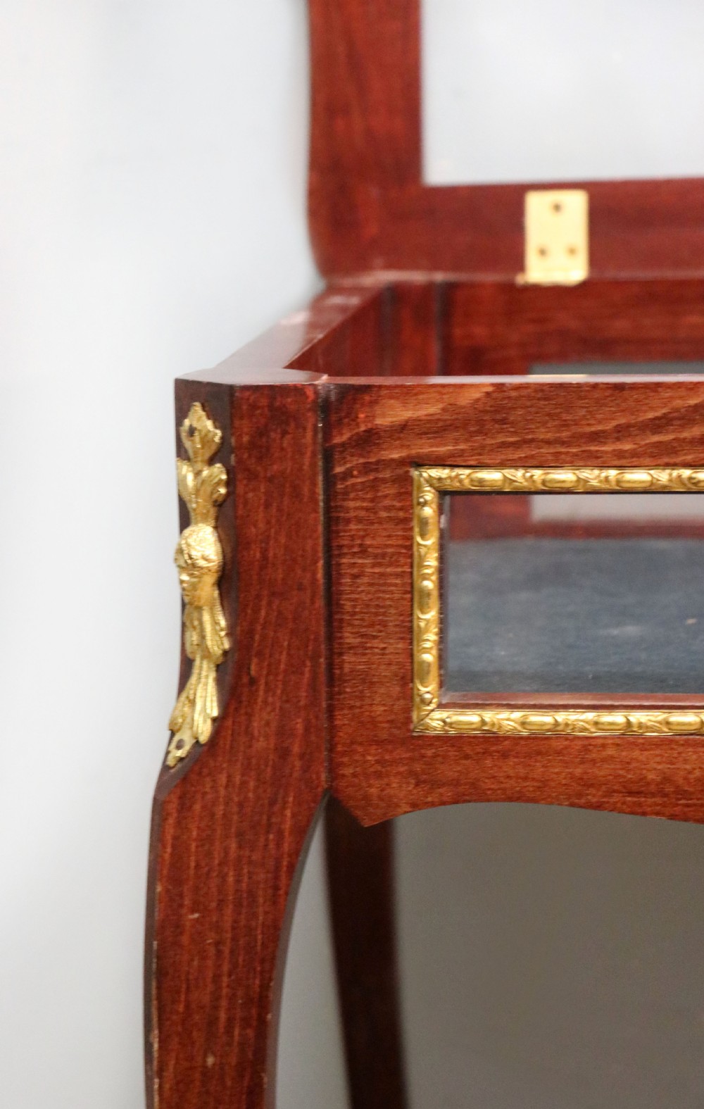 A French Louis XV style glazed bijouterie table in dark hardwood with cabriole legs, gilt metal mounts, and blue Breitling lettering on the glass top. View XXII