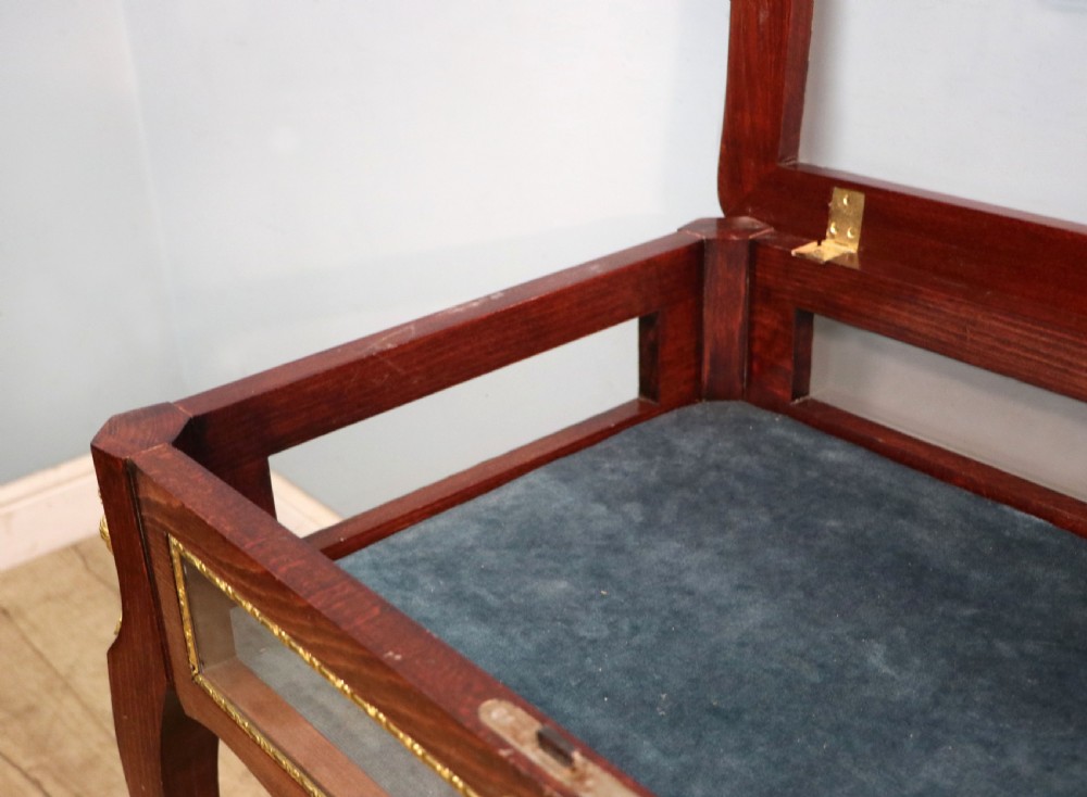 A French Louis XV style glazed bijouterie table in dark hardwood with cabriole legs, gilt metal mounts, and blue Breitling lettering on the glass top. View XXV