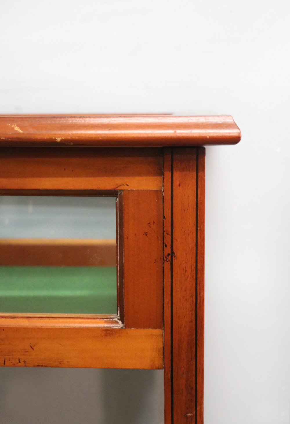 A glazed yew wood bijouterie display table featuring a green velvet interior lining, lower undertier, and Breitling 1884 logo printed on the top glass. View X