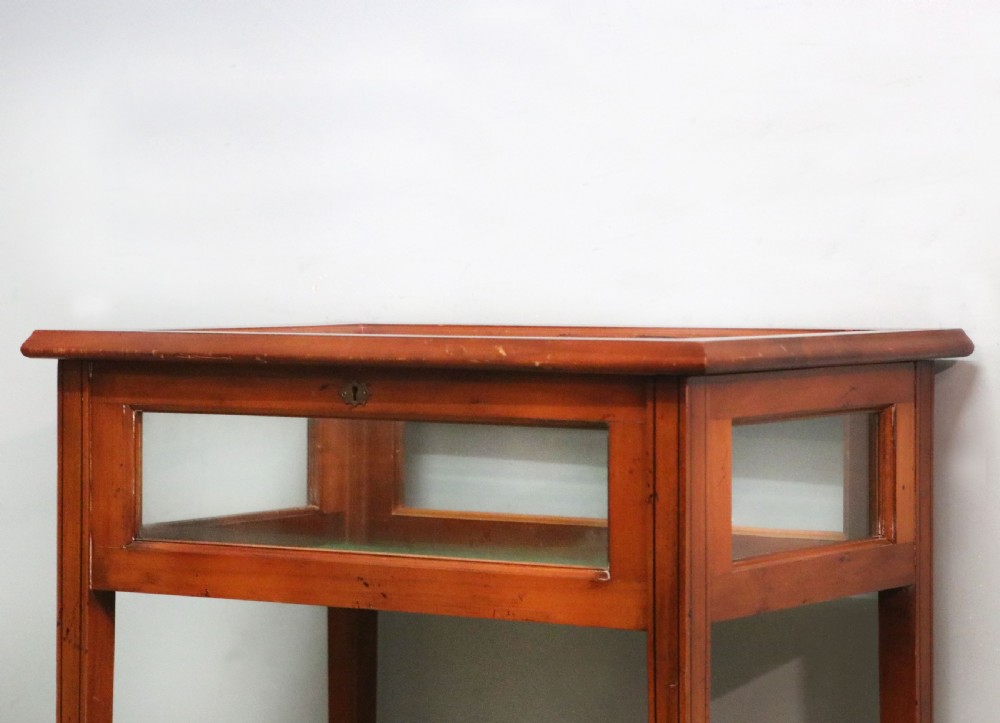 A glazed yew wood bijouterie display table featuring a green velvet interior lining, lower undertier, and Breitling 1884 logo printed on the top glass. View XII